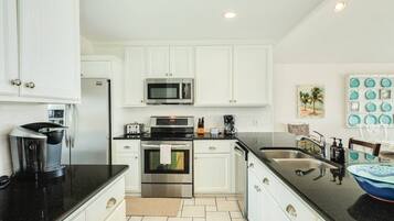 Una cocina moderna con armarios blancos, electrodomésticos de acero inoxidable y encimera negra.