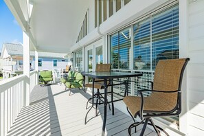 A covered outdoor area with a table and chairs, a railing, and a view of the surrounding buildings.