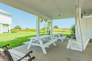A covered outdoor area with picnic tables and a swing chair. - NEW | Waterfront Getaway | Pet-friendly | Just a 2-minute walk to the beach (Galveston)
