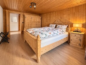 Ein Schlafzimmer aus Holz mit Bett, Kleiderschrank und Nachttisch.