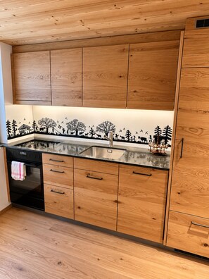 Eine Küche mit Holzausstattung, einer Edelstahl-Spüle und einem schwarzen Backofen.