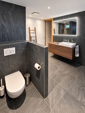 Ein modernes Badezimmer mit Toilette, Bidet und Waschtisch.