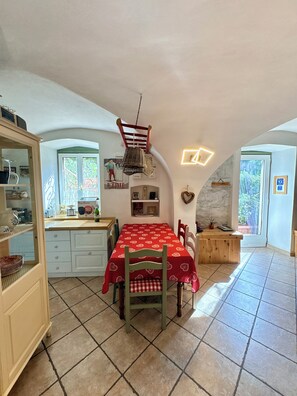 A cozy kitchen with a dining table, chairs, and a hanging light fixture. - Sopramonte Apartment and Annex (Sopramonte)