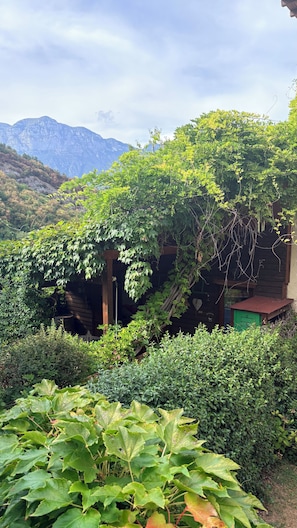 A rustic cabin with a wooden exterior, surrounded by lush greenery and a mountainous backdrop. - Sopramonte Apartment and Annex (Sopramonte)