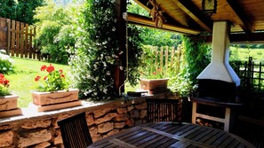 An outdoor patio with a stone wall, a wooden table, and a pizza oven. - Sopramonte Apartment and Annex (Sopramonte)