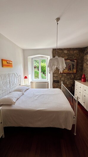A bedroom with a bed, a window, a stone wall, and a red vase. - Sopramonte Apartment and Annex (Sopramonte)