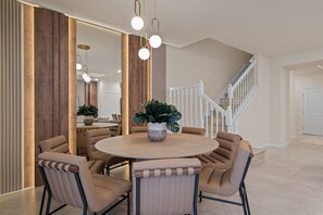 A dining area with a round table, chairs, a potted plant, and a staircase in the background. - 5BR townhouse sleeps 14 with game room (Clermont)