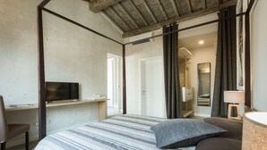 Ein Schlafzimmer mit Bett, Schreibtisch, Fernseher und angrenzendem Badezimmer.
