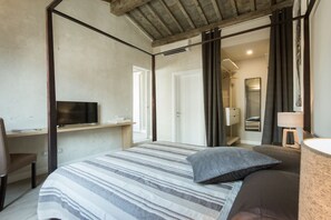 Ein Schlafzimmer mit Bett, Schreibtisch, Fernseher und angrenzendem Badezimmer.
