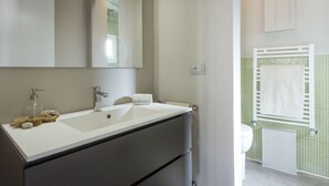 Ein Badezimmer mit einem weißen Waschbecken, einem Spiegel, einem Handtuchhalter und einer Toilette.