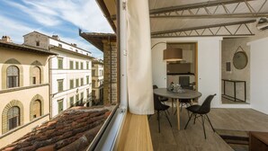 Ein Balkon mit Essbereich, einer Küche und Blick auf alte Gebäude.