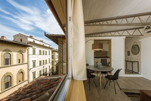 Ein Balkon mit Essbereich, einer Küche und Blick auf alte Gebäude.