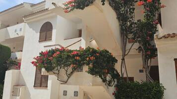 Un edificio con fachada blanca, una escalera y enredaderas con flores.