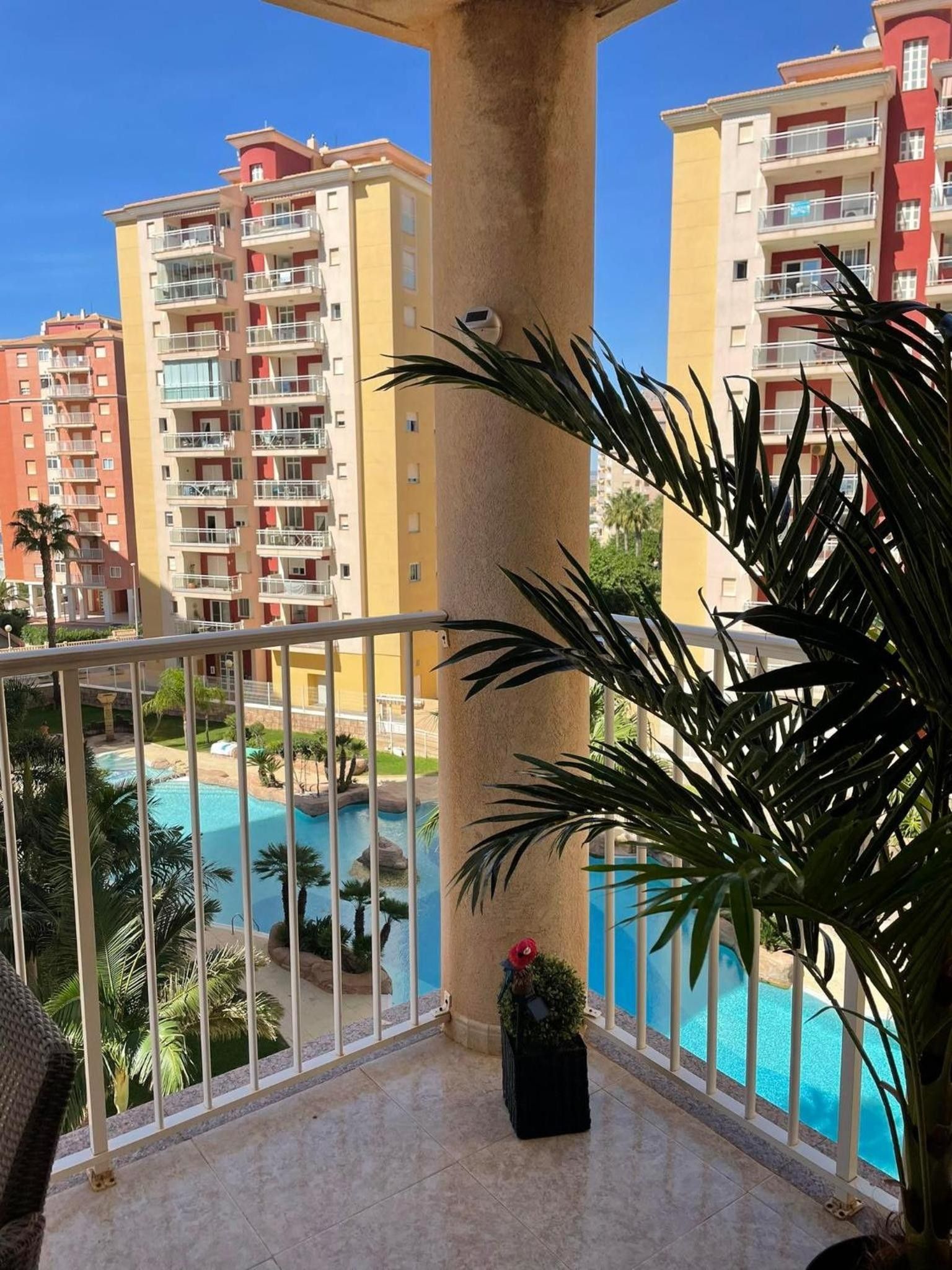 A balcony with a view of a swimming pool and adjacent buildings.