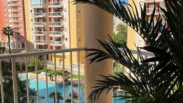 A balcony with a view of a swimming pool and adjacent buildings.