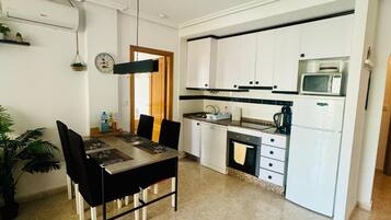 Una cocina moderna con armarios blancos, microondas y cafetera.