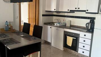 Eine moderne Küche mit weißen Schränken, einer schwarzen Arbeitsplatte und einem Essbereich mit Tisch und Stühlen.