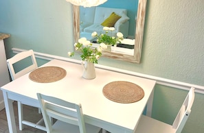 A dining table with two chairs, a vase with white flowers, and a mirror above the table. - Pool-view condo at Boardwalk Beach Resort (Myrtle Beach)