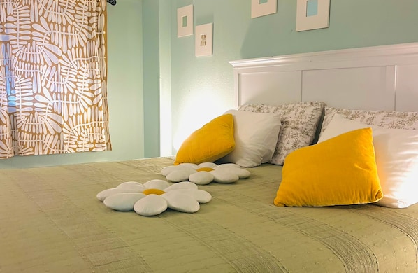 A bed with a white headboard, multiple pillows, and a floral-patterned curtain. - Pool-view condo at Boardwalk Beach Resort (Myrtle Beach)