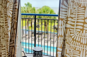 A balcony with a pool, chairs, and a view of the ocean. - Pool-view condo at Boardwalk Beach Resort (Myrtle Beach)