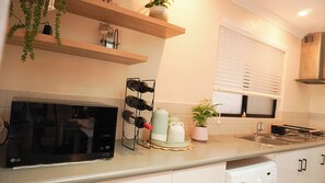 A kitchen with a microwave, wine rack, and a window with blinds.