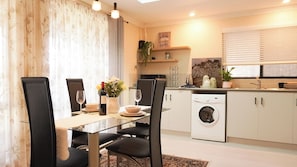 A modern kitchen with a built-in washing machine, a dining area with a glass table, and a kitchen island.
