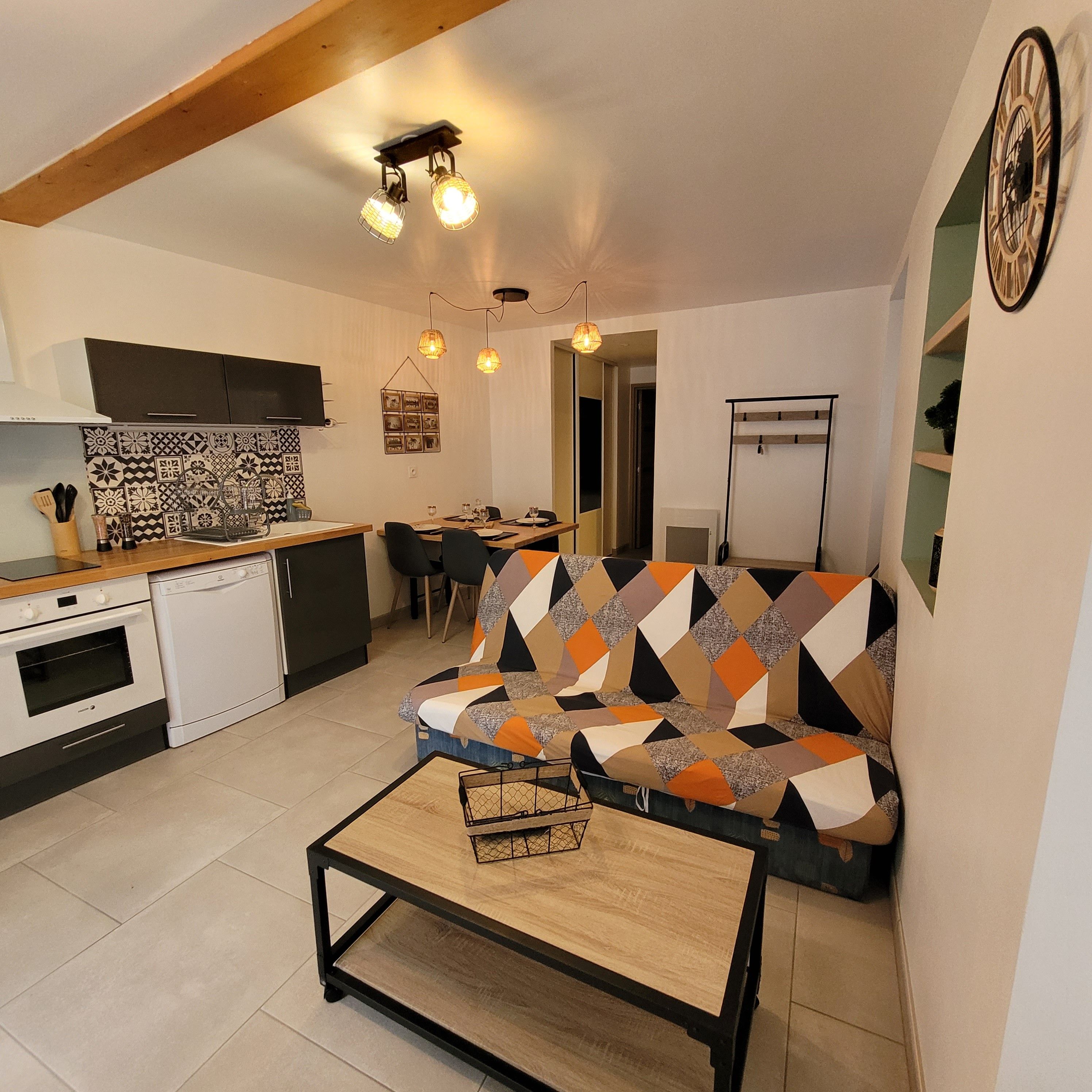 A compact living space with a kitchenette, a sofa, a dining table, and a television.