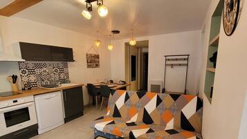 A compact living space with a kitchenette, a sofa, a dining table, and a television.