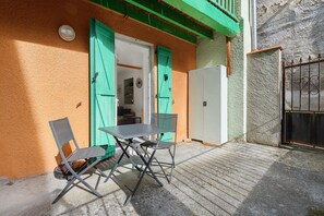 A patio with a table and chairs, a refrigerator, and a gate.