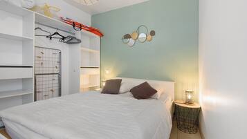 Une chambre à coucher comprenant un lit, une armoire, un étendoir et un miroir fixé au mur.