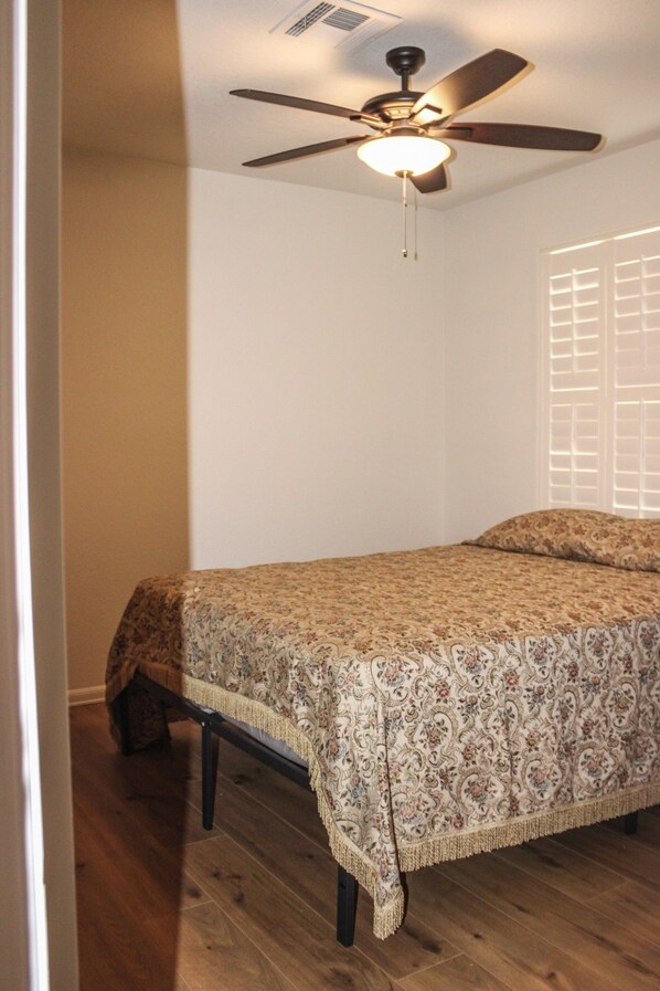 A bedroom with a bed, a ceiling fan, and a window with blinds.