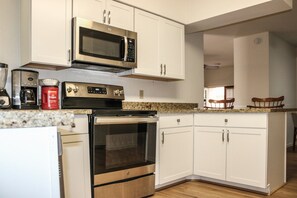 A kitchen with white cabinets, a microwave, a coffee maker, and an oven.