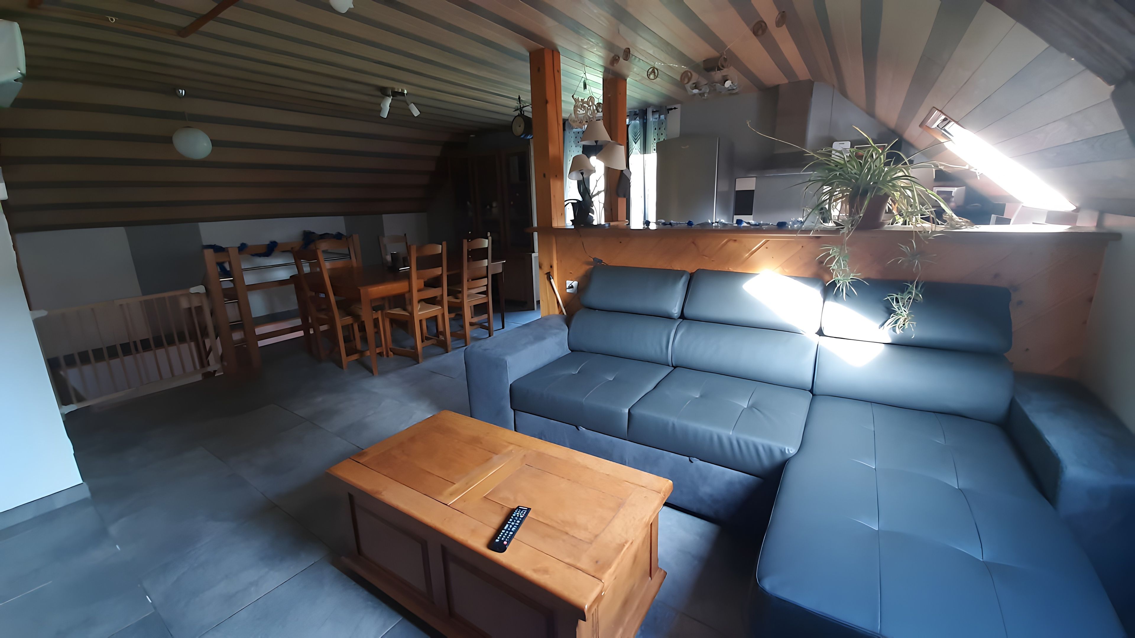 Una sala moderna con un sofá modular, una mesa de centro de madera y un comedor con sillas.
