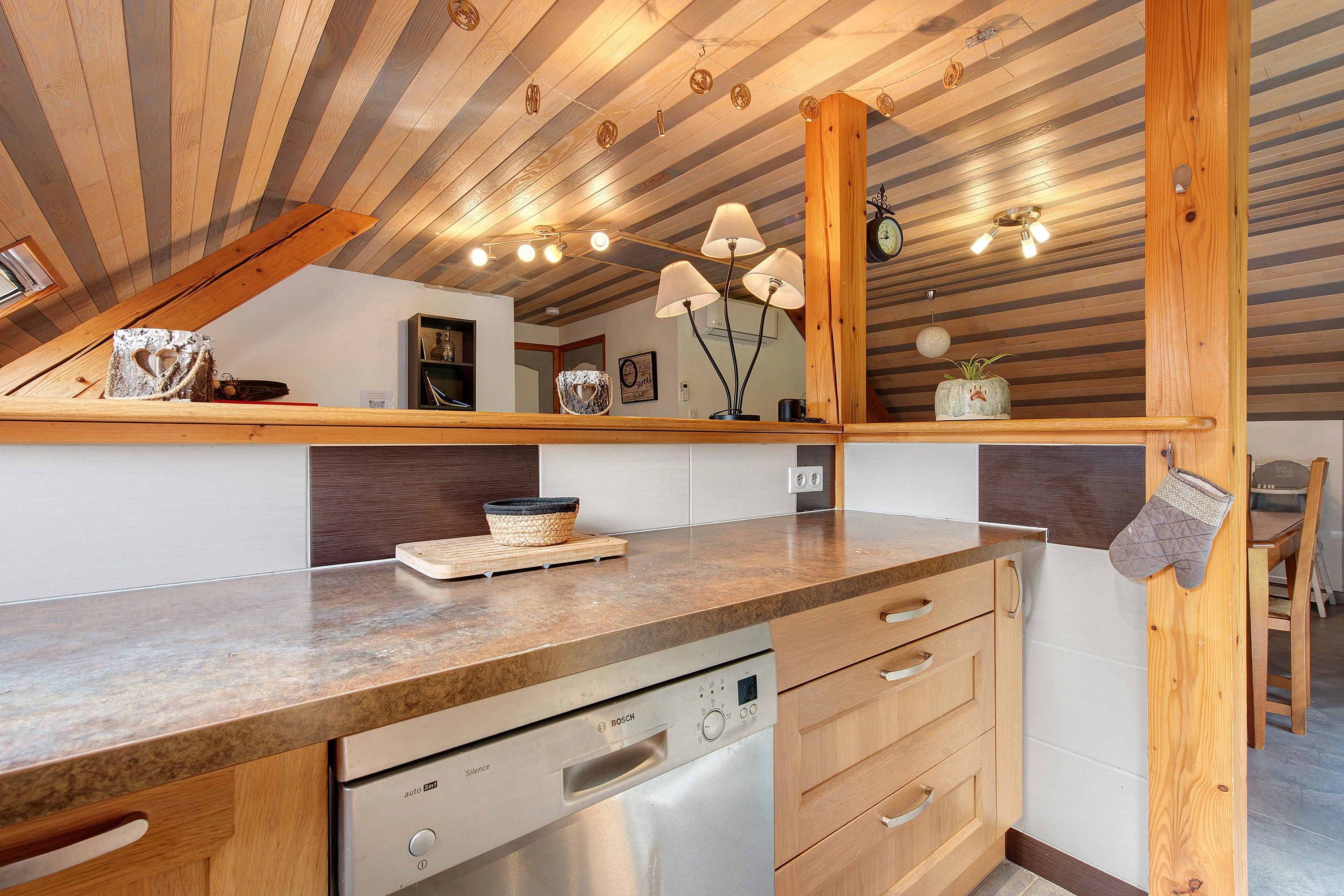 A modern kitchen with wooden cabinetry, a Bosch dishwasher, and a countertop with a woven basket.