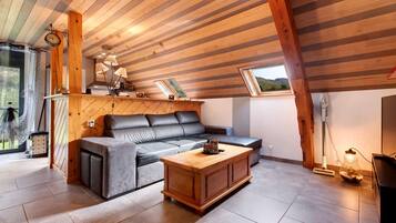 A modern living room with a wooden ceiling, a leather sofa, a wooden coffee table, and a view of the outdoors.