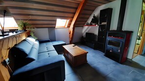 Ein Loft-Wohnbereich mit integriertem Sofa, einem Holztisch, Kamin und Fernseher.