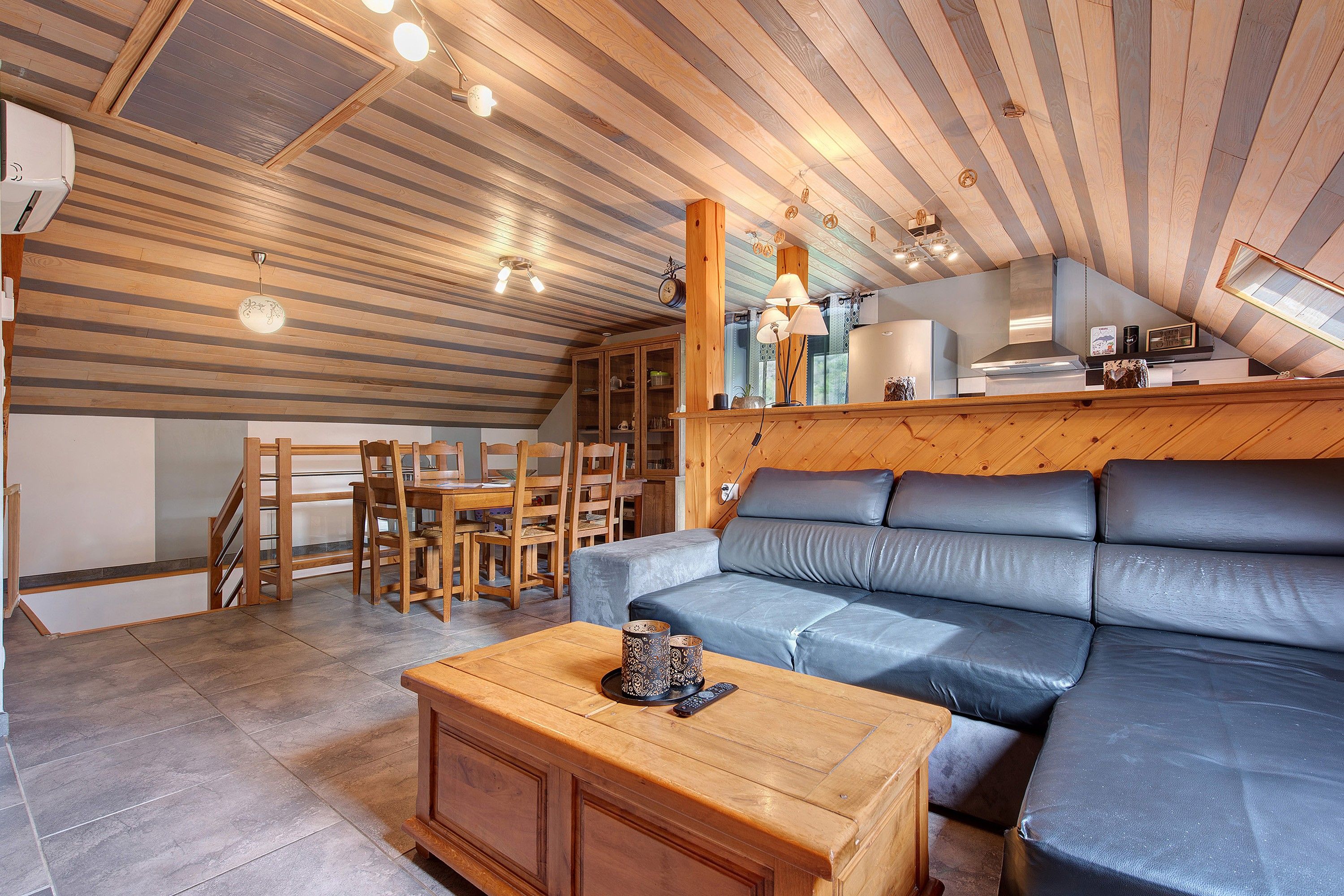 A cozy living room with a sofa, wooden coffee table, and a dining area with chairs and a table.