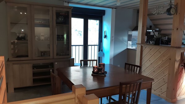 Ein Essbereich mit Holztisch und Stühlen, einem Schrank mit Glastüren und Blick durch ein Fenster.