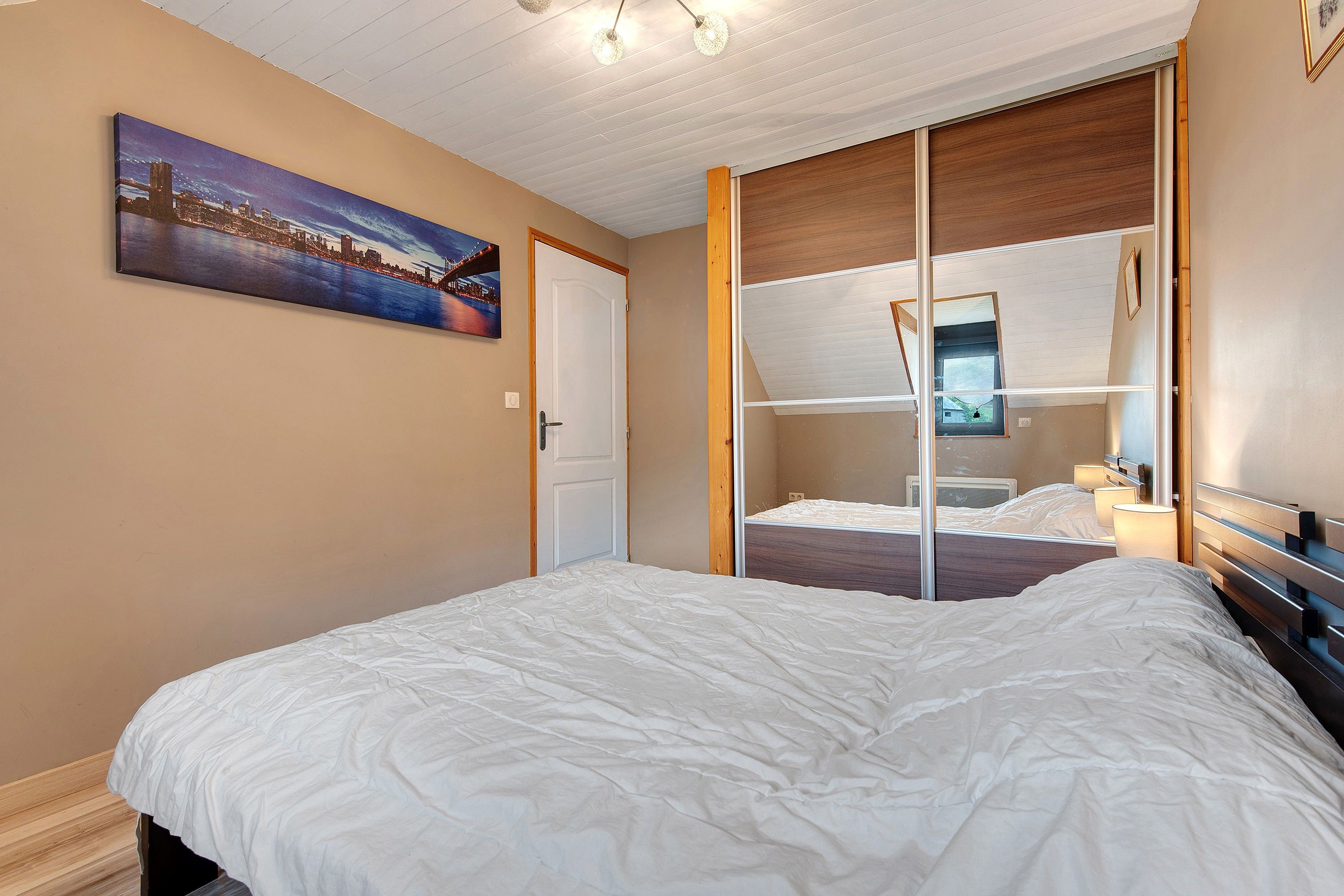 Une chambre d’hôtel avec un lit, une porte, une fenêtre et un tableau au mur.