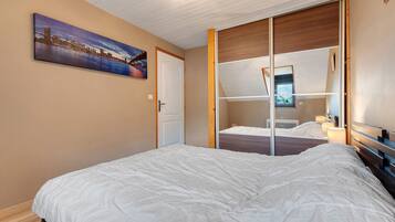 Une chambre d’hôtel avec un lit, une porte, une fenêtre et un tableau au mur.