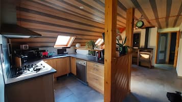 A compact kitchen with a skylight, wooden cabinets, a dishwasher, and a stove.