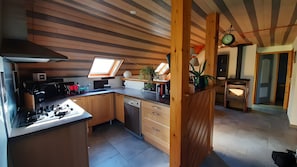A compact kitchen with a skylight, wooden cabinets, a dishwasher, and a stove.