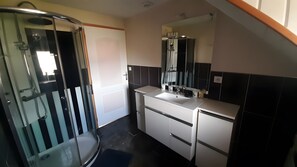 Un bagno moderno con cabina doccia in vetro, lavandino bianco e uno specchio grande.