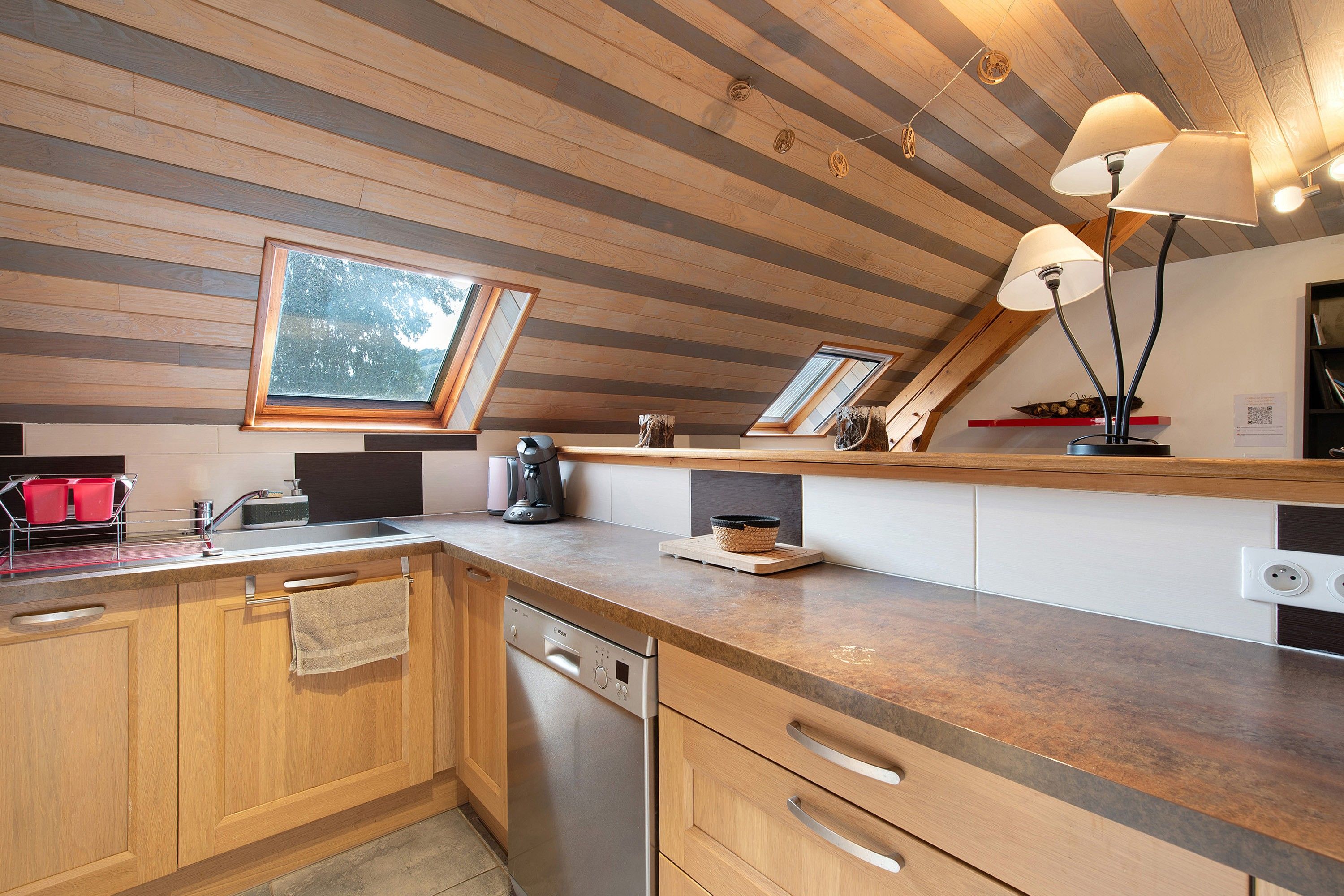 A modern kitchen with wooden cabinetry, a Bosch dishwasher, and a countertop with a coffee maker and kettle.