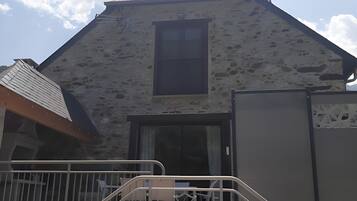 Un bâtiment doté d’une façade en pierre, d’une fenêtre centrale et d’un escalier menant à un balcon.