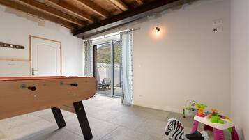 Habitación con mesa de billar, puerta corrediza de vidrio que da a un espacio exterior y juguetes infantiles.