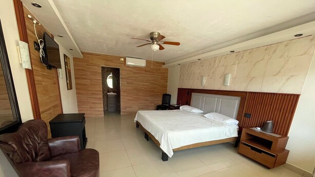 A bedroom with a bed, a chair, a TV, and a ceiling fan. - MARIA BONITA BY CHAVIRA NUEVO LAREDO (Nuevo Laredo)