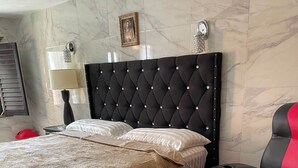 A bed with a tufted headboard, a red and black chair, and a framed picture on the wall. - MARIA BONITA BY CHAVIRA NUEVO LAREDO (Nuevo Laredo)
