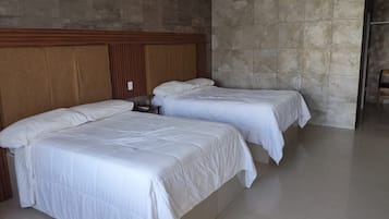 Una habitación con dos camas, cabecera de madera y pared de piedra.