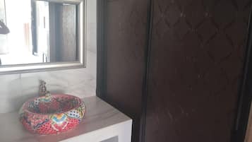 Un baño con lavamanos de mármol, un espejo y una puerta oscura con diseño.